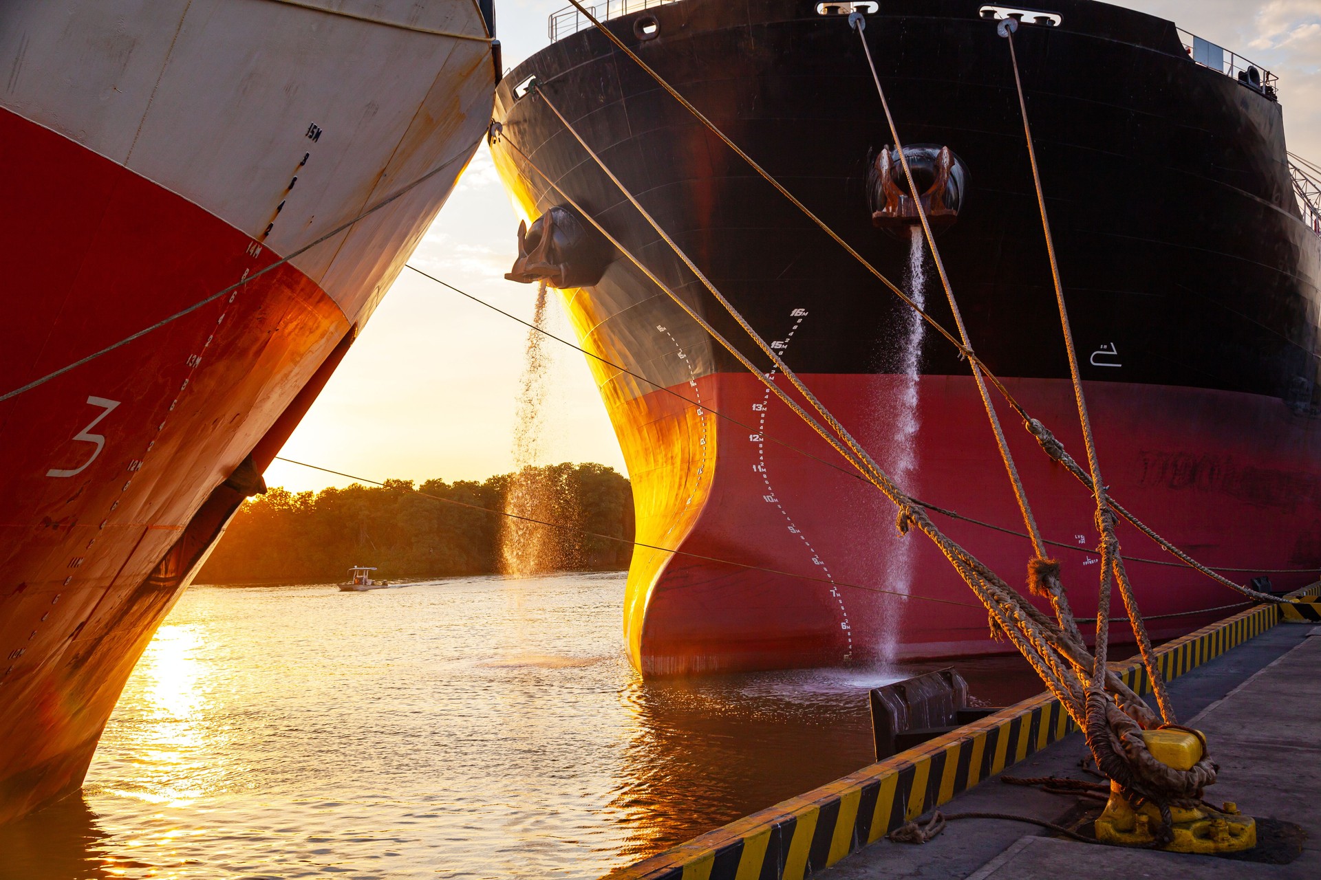 A cargo ship moored to the mooring bollard of the seaport with ropes.